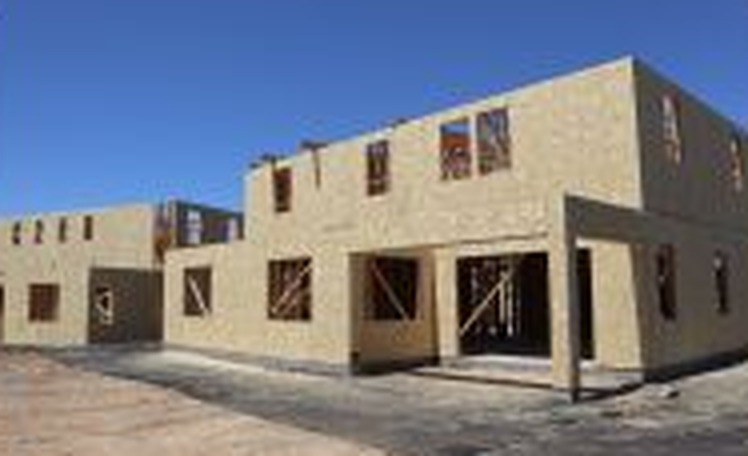 New residential construction framing under a blue sky