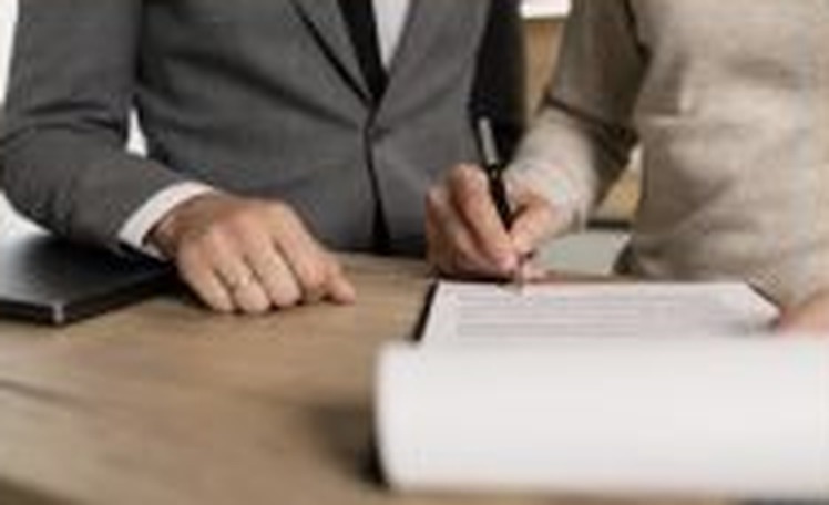 Two people reviewing paperwork across a conference table